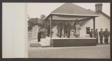 [King George VI, Queen Elizabeth and assorted British Army generals standing on a reviewing platform.]