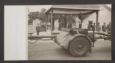 [King George VI, Queen Elizabeth and assorted British Army generals standing on a reviewing platform, as artillery is towed past.]