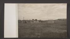 [Quonset hut barracks beside field]