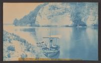 [Young man fishing in small boat with awning]