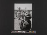 [Man playing trumpet with men in costume in background, Peru]