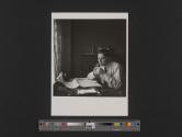[Arthur Koestler lighting a cigarette at his desk]