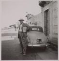 [Man standing near car]