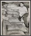 [Man sitting on sacks of cane sugar]