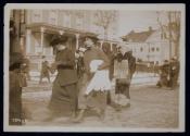[Women marching down the street during the Suffrage Hike, woman holding a sign that reads "I Was a Voter in California Get Busy New York"]