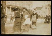[Women marching down the street during the Suffrage Hike, woman holding a sign that reads "I Was a Voter in California Get Busy New York"]