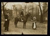 [Elisabeth Freeman dressed as a gypsy, standing next to policeman on horse and man with a camera]