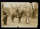 [Elisabeth Freeman dressed as a gypsy, standing next to policeman on horse and man with a camera]