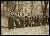 [Group of ten women with cloaks and walking sticks, holding a banner for the "Votes for Women Pilgrimage from New York City to Washington DC"]