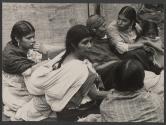 [Group of women and children seated on the ground.]