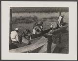 [People in boat, one woman holding large clay pot, on a river in Mexico]