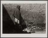 [Woman standing against wall in shawl with shadow]