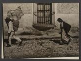 [Woman and man walking on cobblestone street]