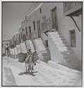 [Man and mule walking down village street, Greece]