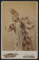 [Woman in floral fabric costume posing with a lorgnette]