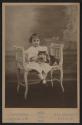 [Girl holding cat on white scroll arm bench]