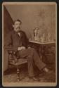 [Man sitting next to monogramed silver service set]