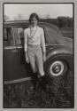 [Woman in equestrian outfit standing beside a Bentley car]