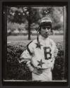 [Jockey standing beside a hedge]