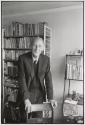 [Man in front of bookshelf]