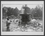 [Woman playing with a dog in a city park fountain]