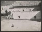 [Street scene from above with man in black vestments]