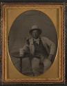 [Man wearing light colored suit, seated and holding pipe]