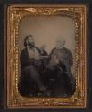 [Two seated men, one pointing toward the other]