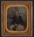 [Boy seated holding hat]