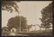 [People in field with tents and flagpoles]