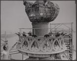 [Man touching torch from scaffolding around the Statue of Liberty]