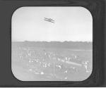 [Biplane flies over a crowd of spectators]