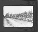 [Soldiers seated/gathered beside railroad tracks as train pulls away]